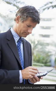 Businessman outdoors using personal digital assistant