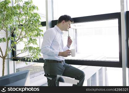 Businessman peering out office window