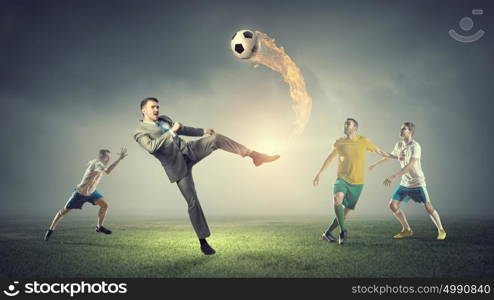 Businessman play ball. Young businessman in suit playing football with players outdoors