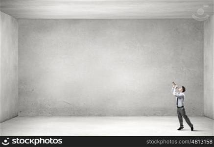 Businessman play pipe. Young businessman in empty cement room playing pipe