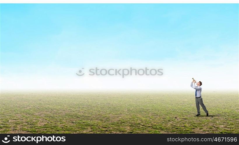 Businessman play pipe. Young businessman in green field playing pipe
