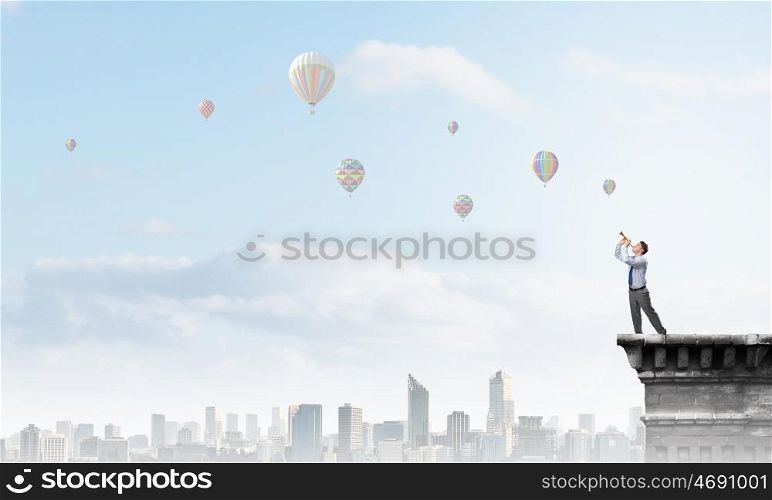 Businessman play pipe. Young businessman on building top playing pipe