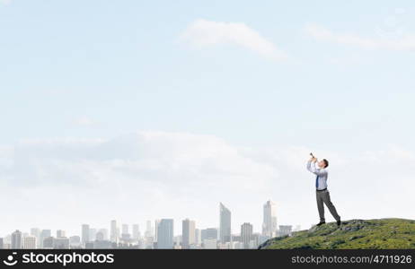 Businessman play pipe. Young businessman on hill top playing pipe