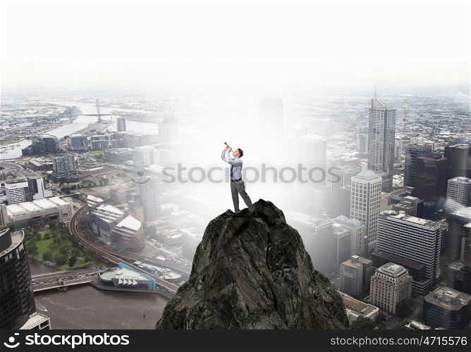 Businessman play pipe. Young businessman on rock top playing pipe