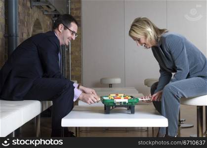 Businessman playing foosball with a businesswoman