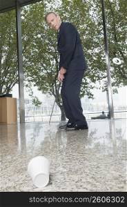 Businessman playing golf in an office