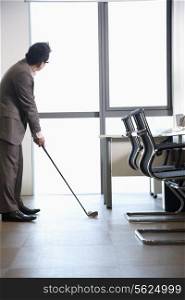 Businessman playing golf in his office