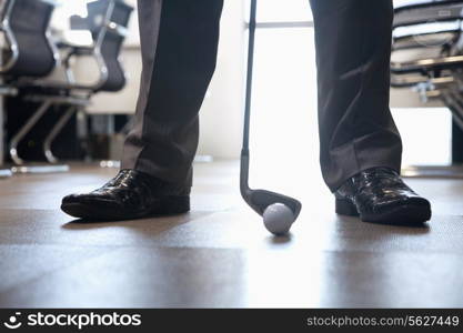 Businessman playing golf in his office, close up on feet