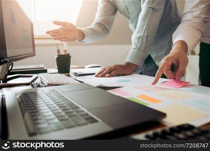Businessman point to the graph of the company financial statements in the paperwork and together analyzing the work room.
