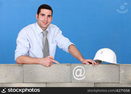 businessman pointing at an at sign on a wall