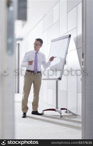 Businessman preparing for presentation on flipchart in office