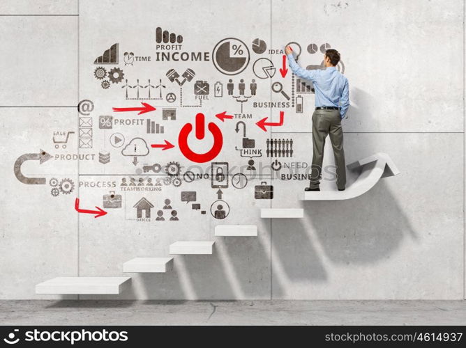 Businessman presenting his ideas. Businessman standing with back and drawing business strategy on wall