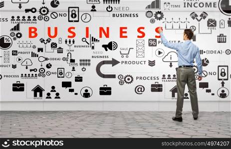 Businessman presenting his ideas. Businessman standing with back and drawing business strategy on wall