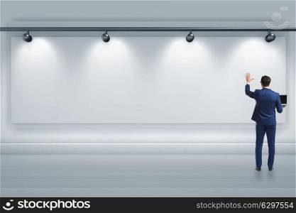 Businessman pressing virtual button on the wall lit with spotlights. Businessman pressing virtual button on the wall lit with spotlig