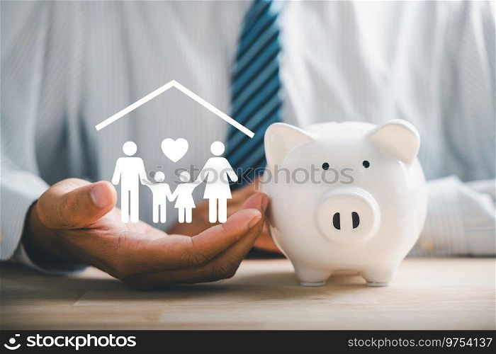 Businessman protects piggybank and holds family icon, showcasing saving, donation, family finance approaches. Illustrating mes of charity, fundraising, superannuation, and financial crisis concept.. Businessman take a position to protect on the piggybank