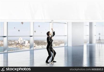 Businessman pulling banner. Young businessman in office and blank banner. Place for text