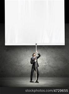 Businessman pulling blank banner. Image of young businessman pulling blank banner. Place for text