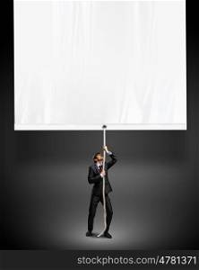 Businessman pulling blank banner. Image of young businessman pulling blank banner. Place for text