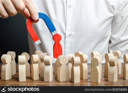 businessman pulls out a red figure of a man from the crowd with the help of a magnet. toxic, uncompetent worker. Increase team efficiency, productivity. leader manages the business and forms a team.. businessman pulls out a red figure of a man from the crowd with the help of a magnet. toxic, non-competent worker. Increase team efficiency, productivity. leader manages the business and forms a team.