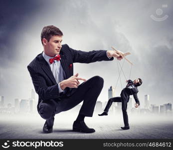 Businessman puppeteer. Image of young businessman puppeteer. Leadership concept