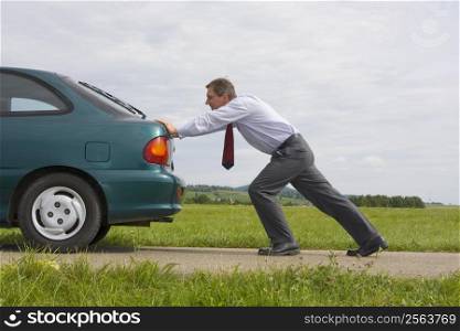 Businessman pushing a car with empty fuel tank