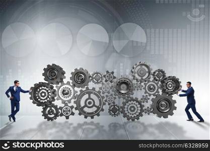 Businessman pushing cog wheels in business concept