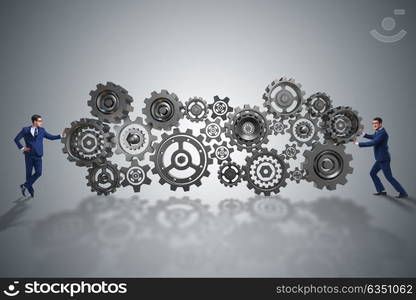 Businessman pushing cog wheels in business concept