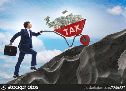 Businessman pushing tax wheelbarrow uphill