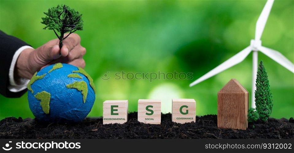 Businessman put tree on paper earth with ESG symbol cube as concept for forest regeneration by ethical corporate company with environmental protection awareness for green environment in future. Alter. Businessman put tree on paper earth with ESG for forest regeneration. Alter