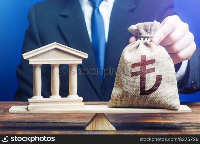 Businessman puts a turkish lira money bag on scales opposite to government state building.Payment of taxes and fees. Financing Social programs. Lending to government projects. Bank deposit