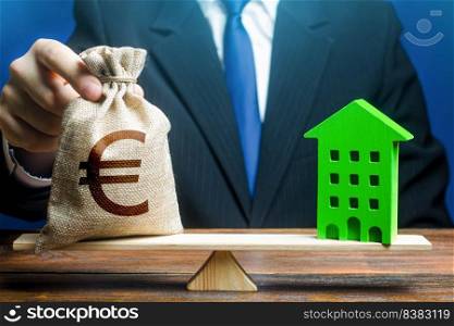 Businessman puts euro money bag on scales and green house. Investment in renovation. Reduced CO2 emissions, energy efficiency. Payback period. Profitability housing of eco technologies.