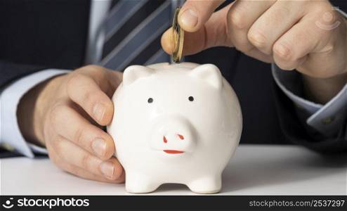 businessman putting coin piggy bank