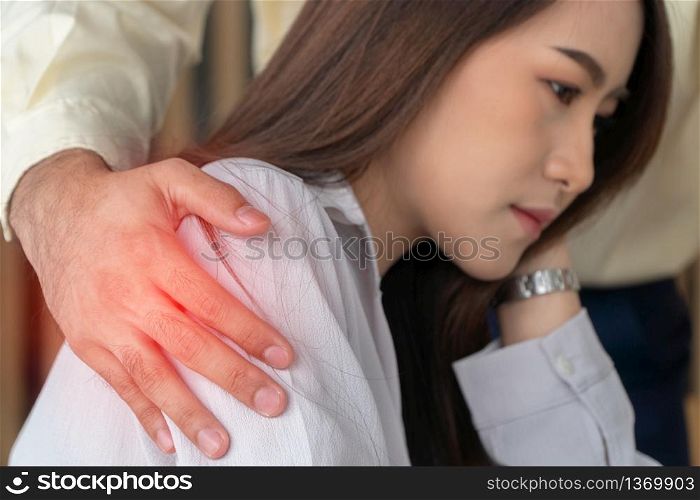 Businessman putting hand on the shoulder of female employee in office at work. She unhappy and feeling displeased with inappropriate actions his boss. Concept of sexual harassment in workplace