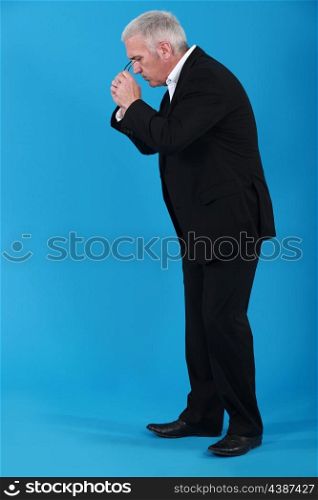 Businessman putting his eyeglasses on to look for an object