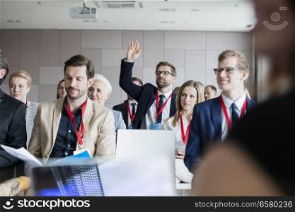 Businessman raising hand during seminar