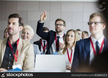 Businessman raising hand during seminar at convention center