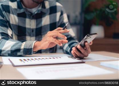 Businessman read information on smartphone while checking finance and accounting report of business.
