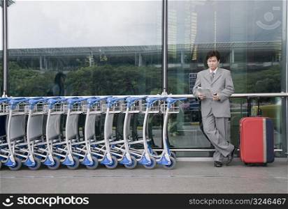 Businessman reading a document and waiting outside an airport