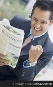 Businessman reading a newspaper and making fists