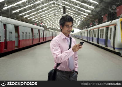 Businessman reading an sms at a train station