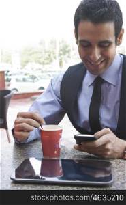 Businessman reading an sms while having coffee , INDIA , DELHI