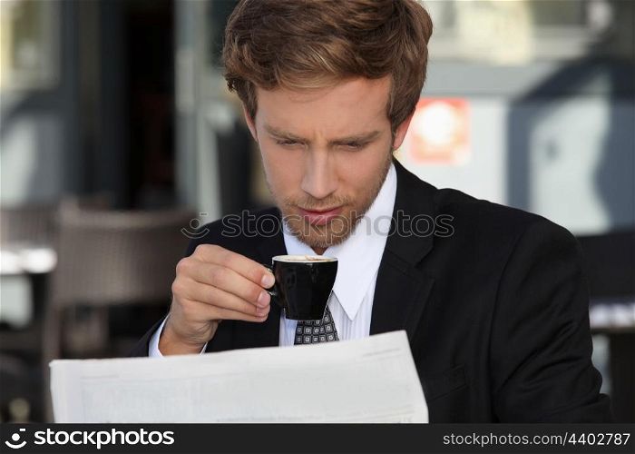 Businessman reading documents and drinking expresso