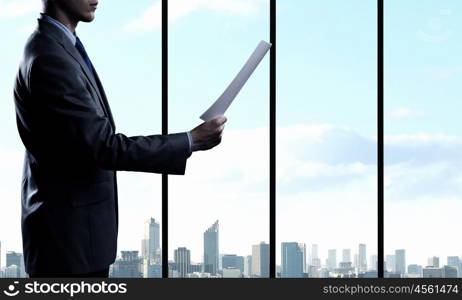 Businessman reading documents. Businessman looking in papers against office window