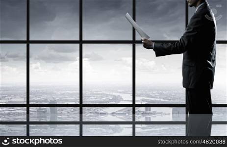 Businessman reading documents. Businessman looking in papers against office window
