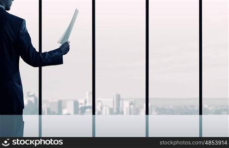 Businessman reading documents. Businessman looking in papers against office window