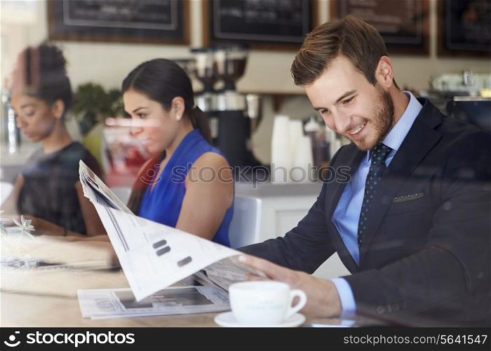 Businessman Reading Newspaper In Coffee Shop