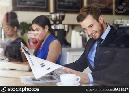 Businessman Reading Newspaper In Coffee Shop