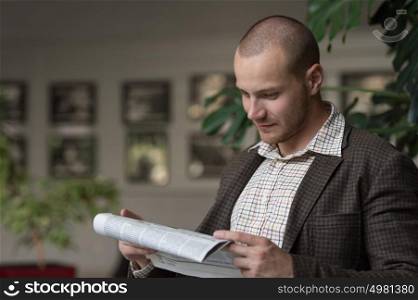 Businessman reading newspaper on chair at office building hall or cafe