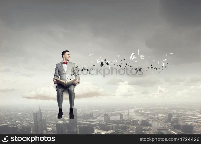 Businessman reading old book. Businessman reading book on the cloud high in sky