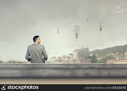 Businessman reading old book. Young businessman reading book sitting on roof of building